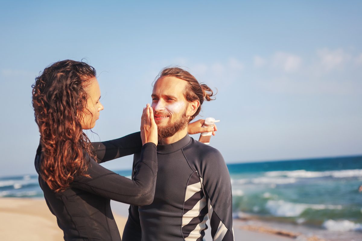 A couple applies zinc oxide on a beach