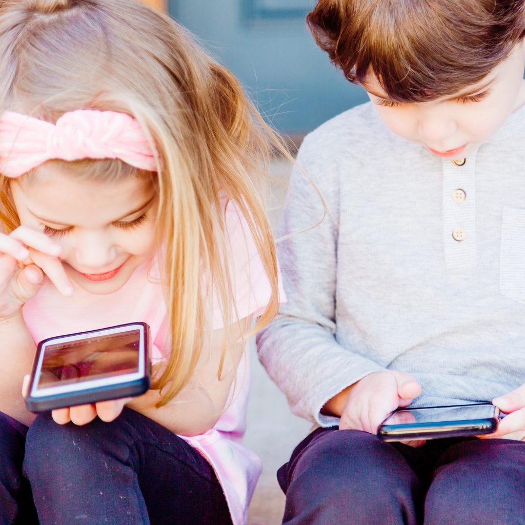 Two kids playing on phones