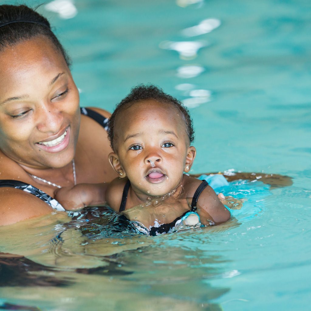 An adult teaching a baby how to swim.