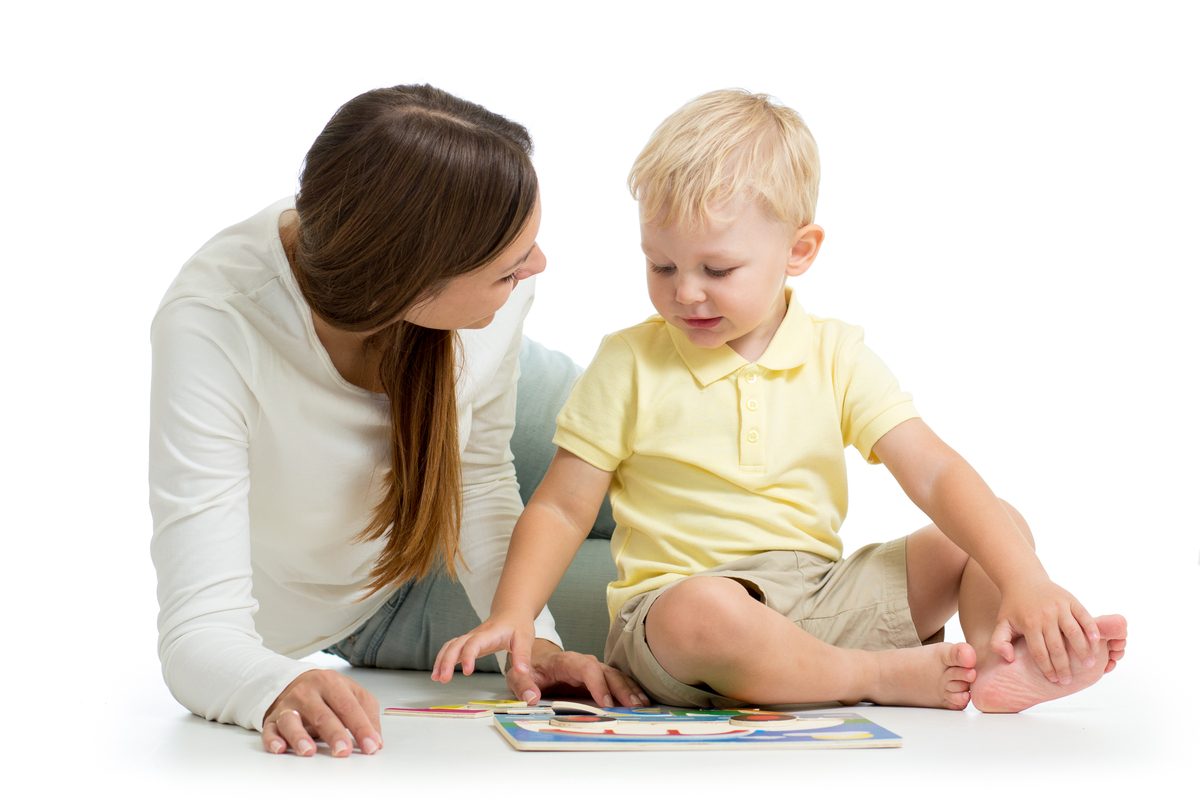 Toddler boy doing puzzle on the floor with mom