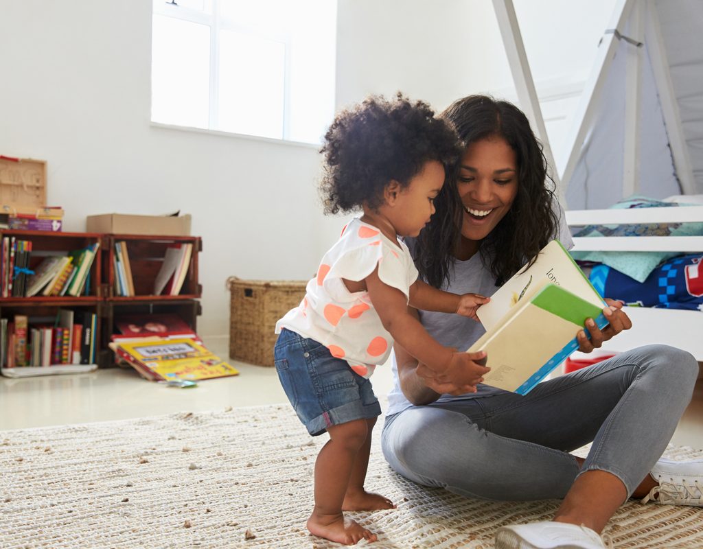 Toddler reading book with her mom
