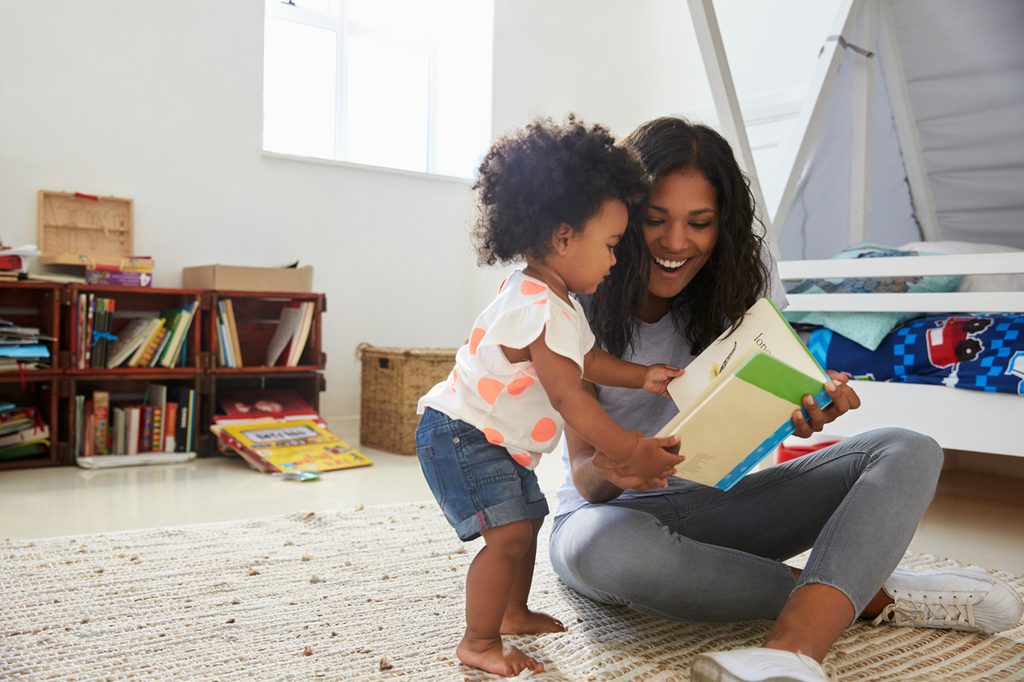 Toddler reading book with mom
