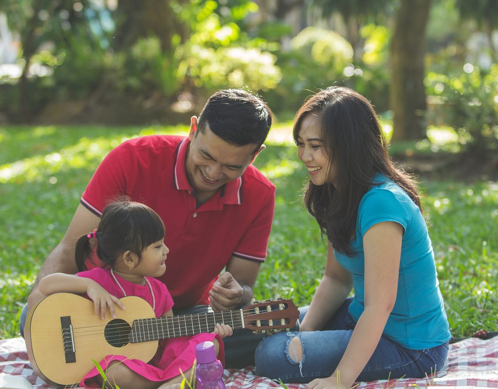 Toddler playing guitar and singing with their parents