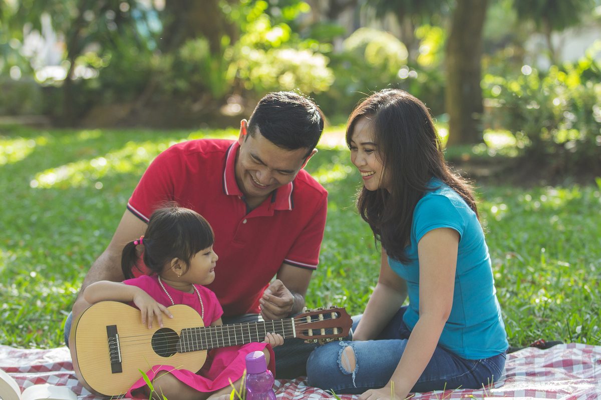 Toddler singing and playing guitar with parents