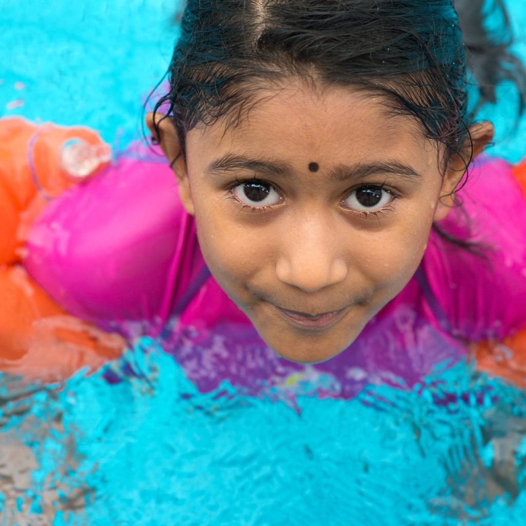 Young Indian girl swimming in a pool with floaties