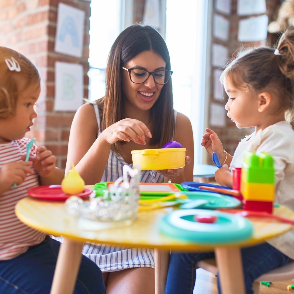 Teacher plays with two small female children