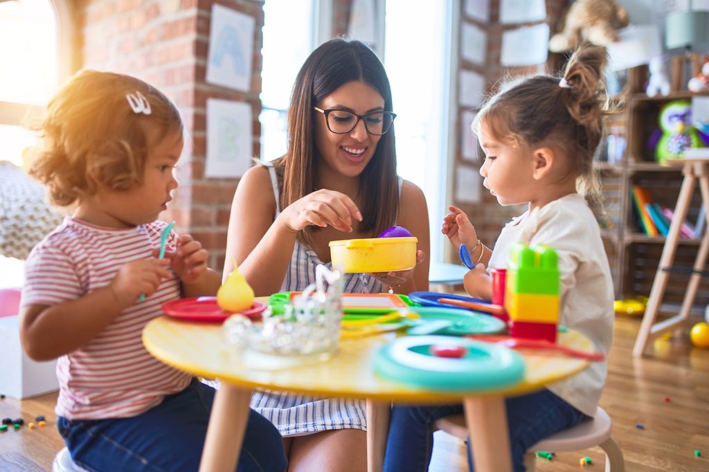 Teacher plays with two small female children.