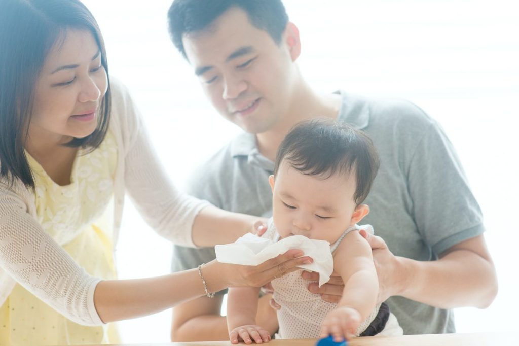 Parents cleaning a baby's face.