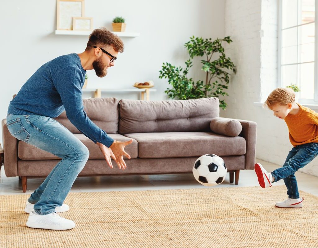 Father and son playing soccer In living room
