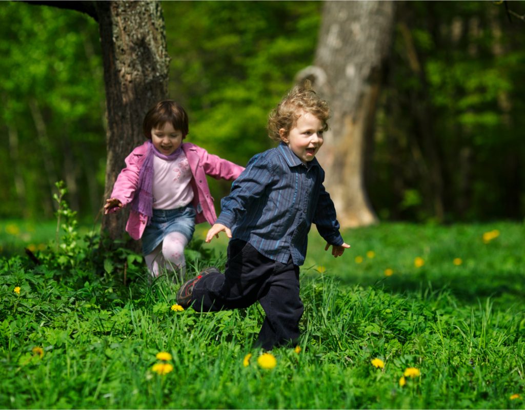 Toddler girl and boy having fun running in the park