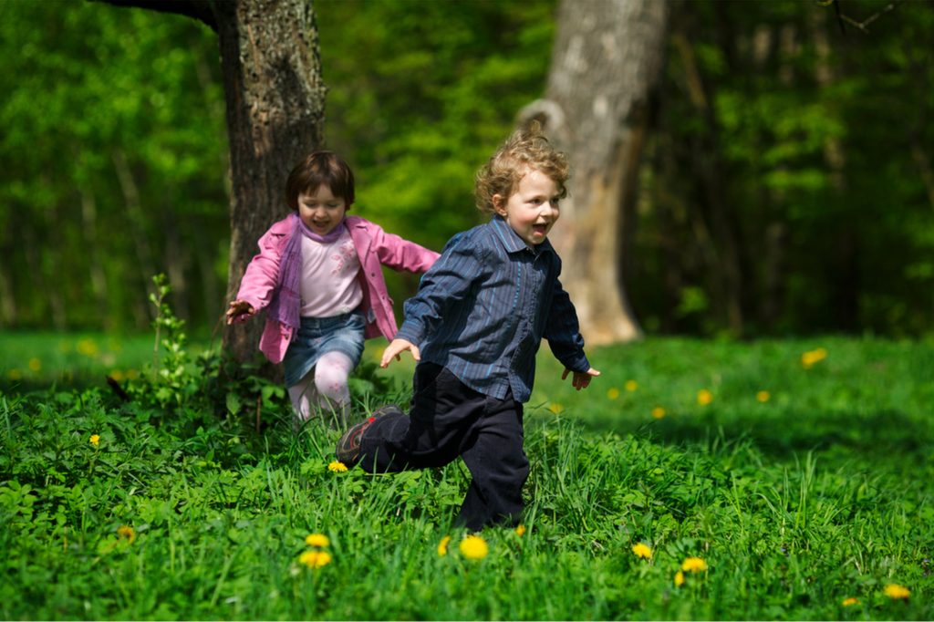 toddler boy and girl running in a park