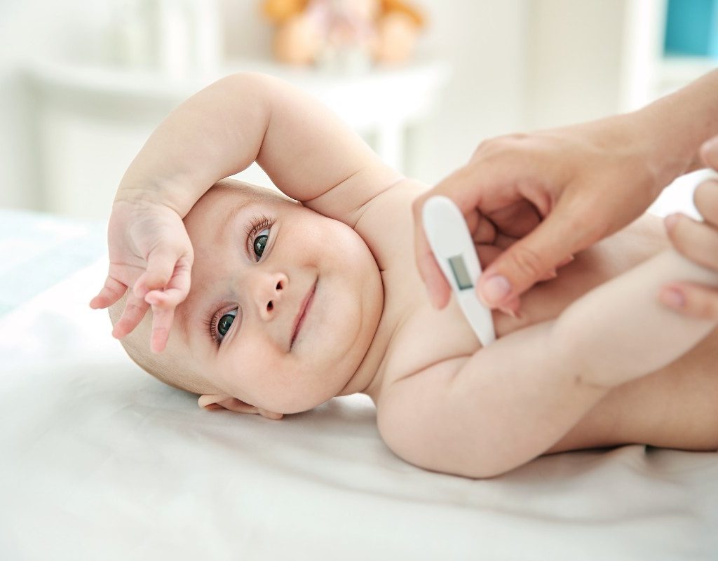 Baby in bed with a thermometer