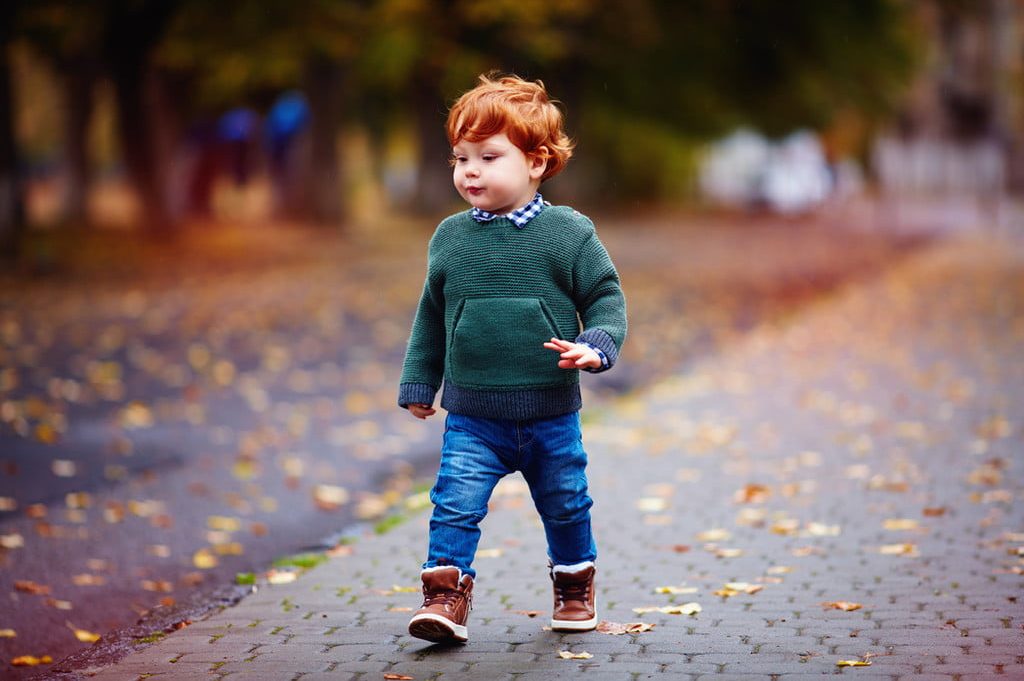 red headed toddler boy walking on road