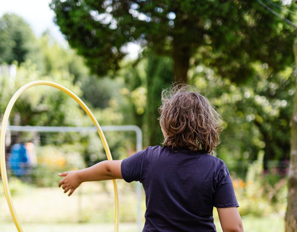 A boy playing with a hula hoop in a backyard