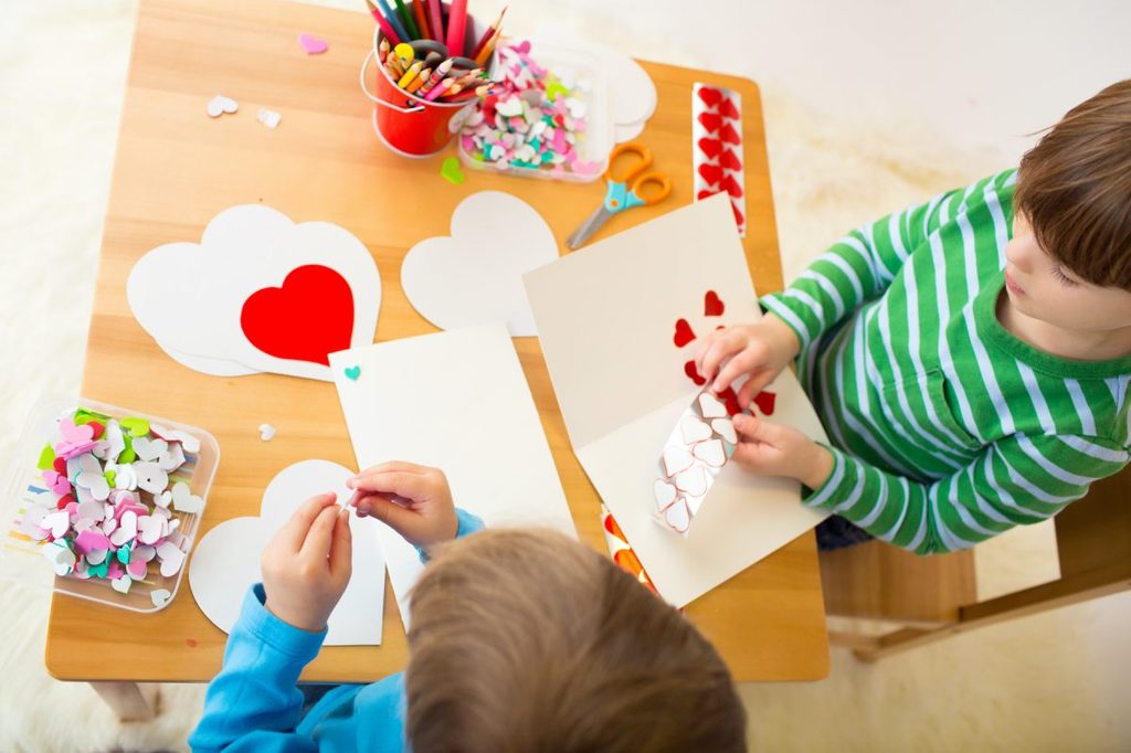 Little kids making Valentine's Day crafts.
