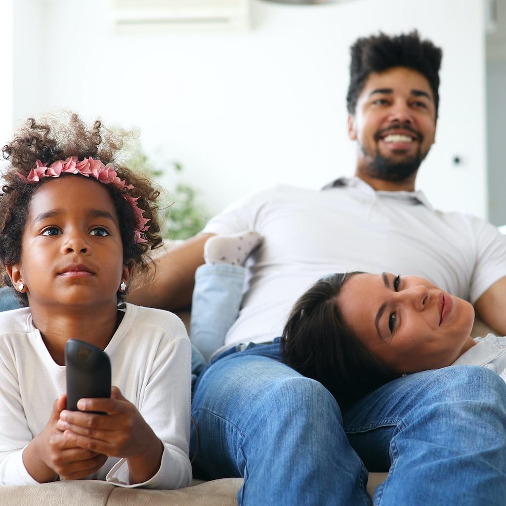 Family of three watching TV on a couch