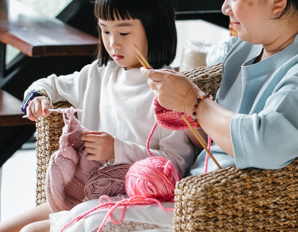girl learning how to knit with her mother