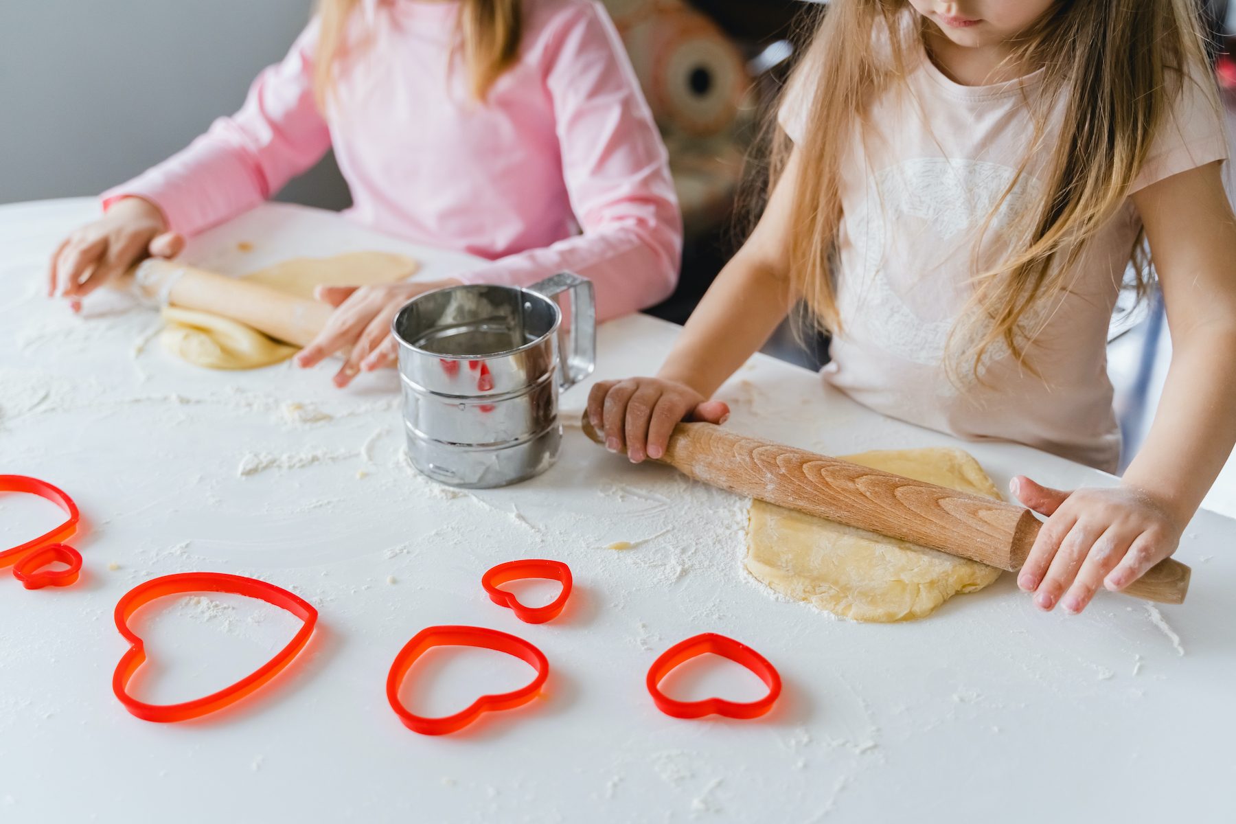Two kids making heart-shaped cookies