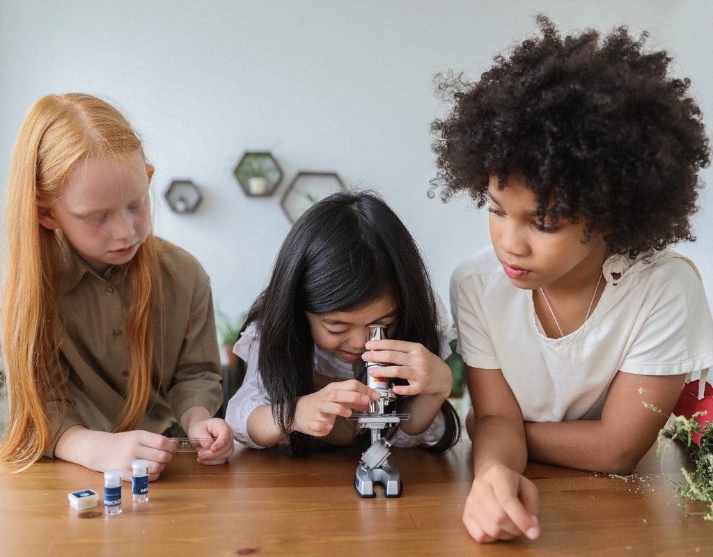 Three young girls using a microscope