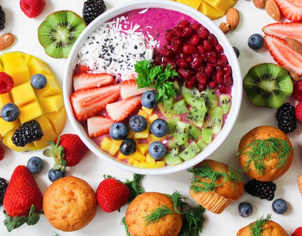 Fruits in a bowl and on a table with muffins