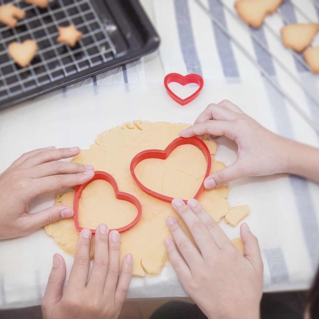 Parent and child making heart-shaped cookies