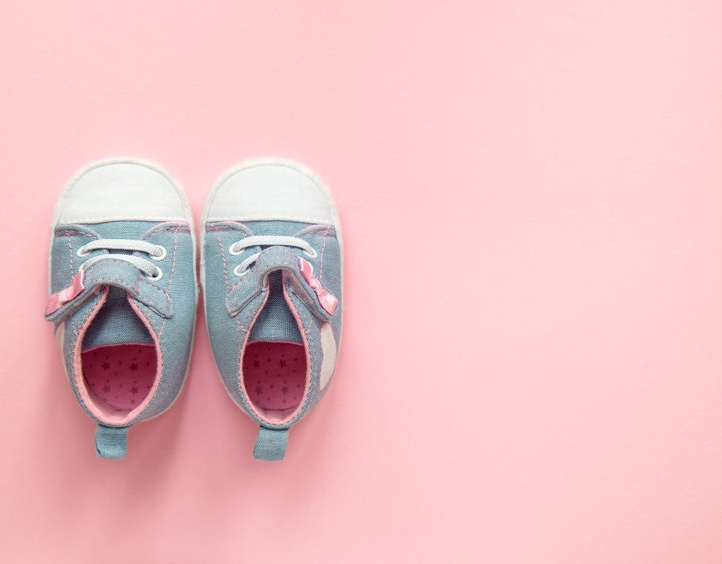 A pair of baby shoes on a pink floor