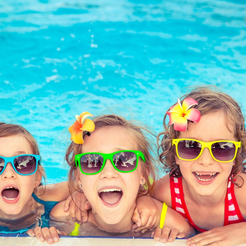 Kids having fun in a pool and wearing sunglasses.