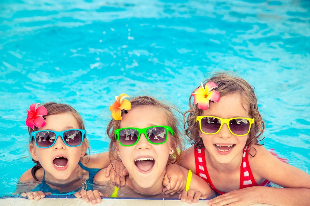Kids having fun in a pool and wearing sunglasses.