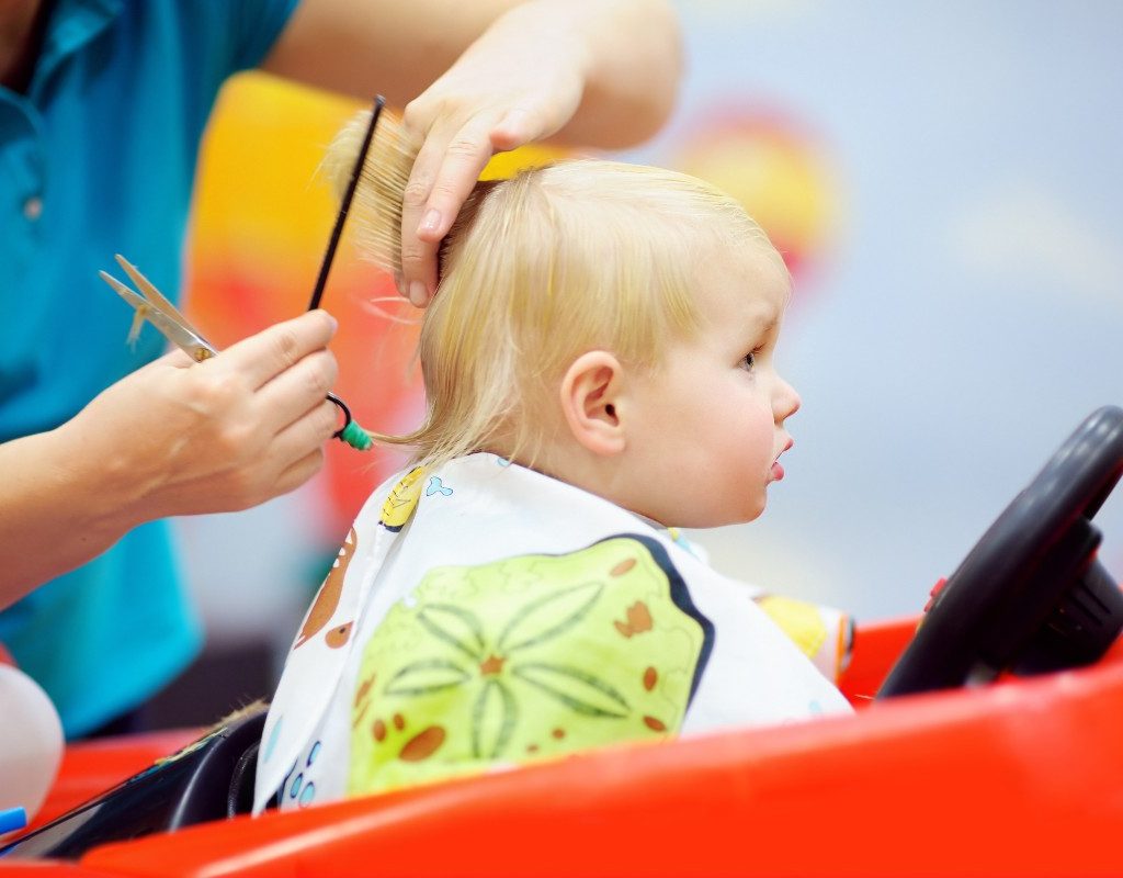 A baby getting a haircut in a salon ride-on chair.