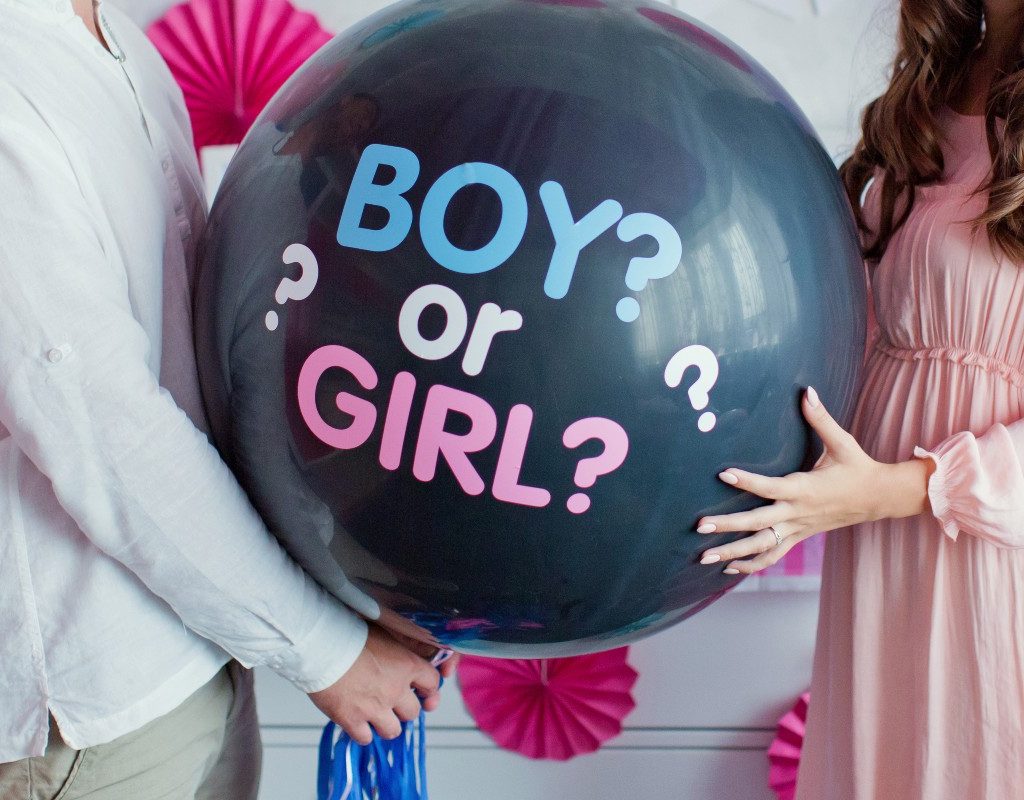A couple holding a gender-reveal balloon