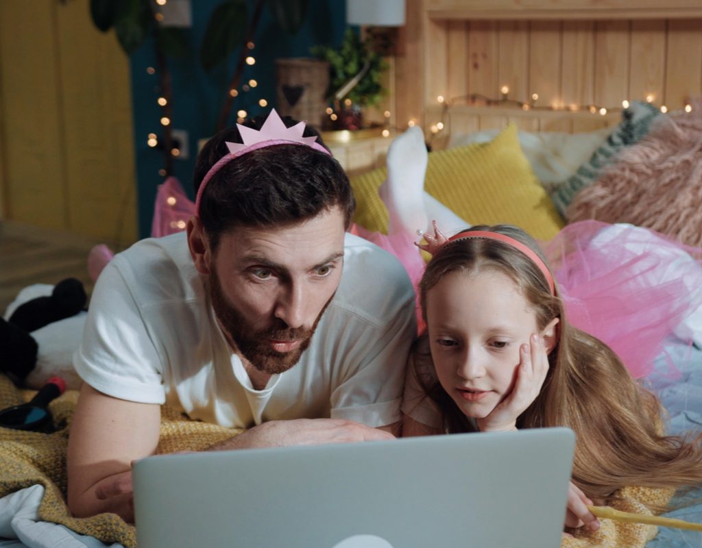 A dad and daughter having fun watching cartoons