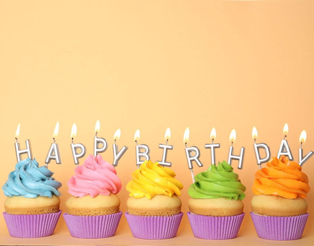 Happy birthday cupcakes in a row with candles