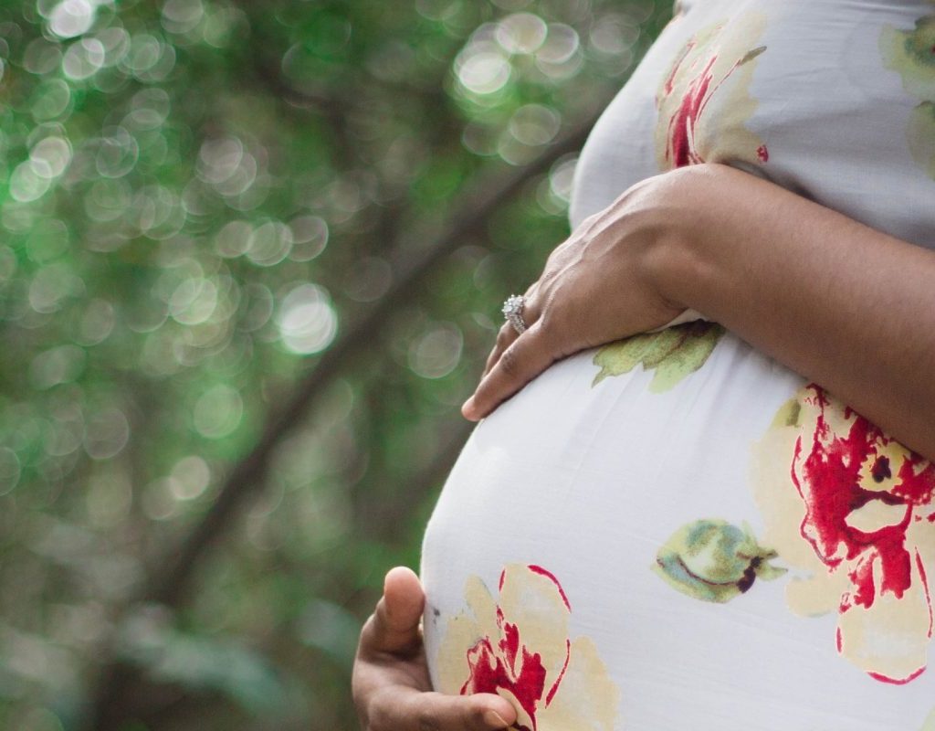 Pregnant married woman standing in a floral gown