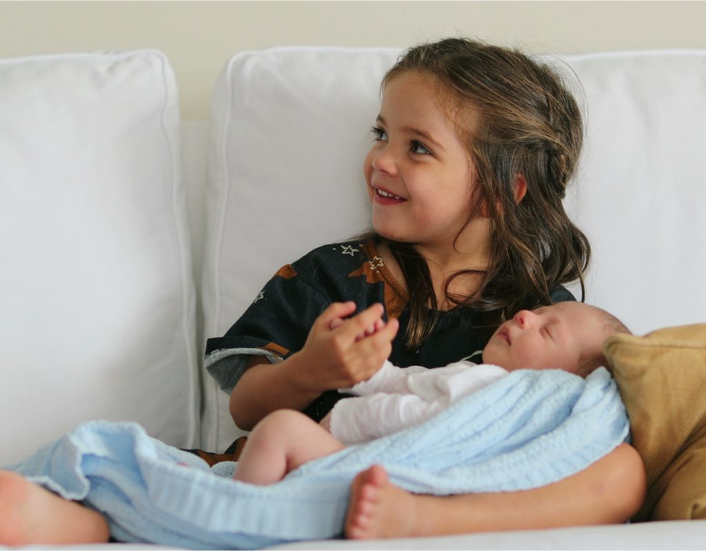 Little girl holding her newborn sibling
