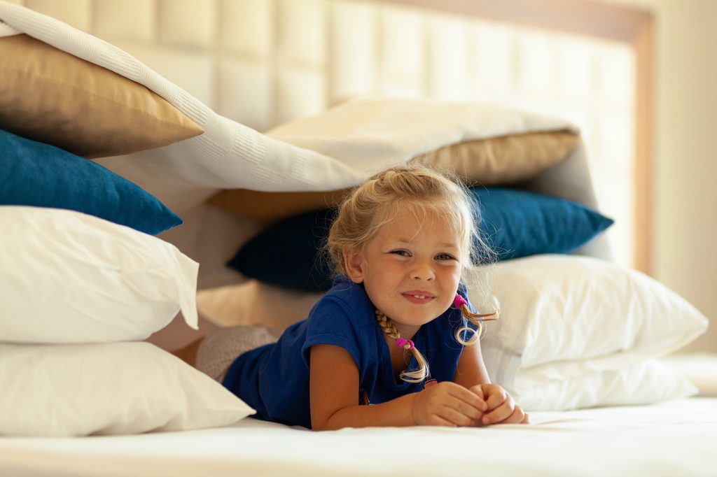 Little girl inside a pillow and blanket fort