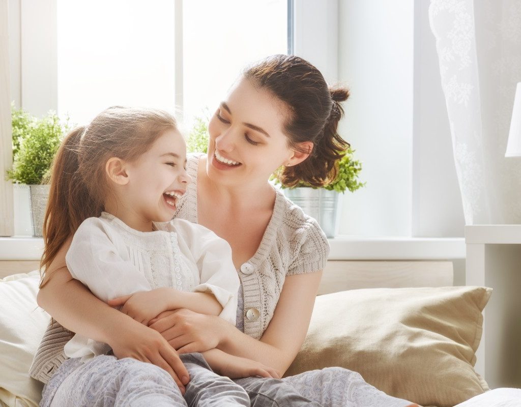 Mother laughing with her young daughter.