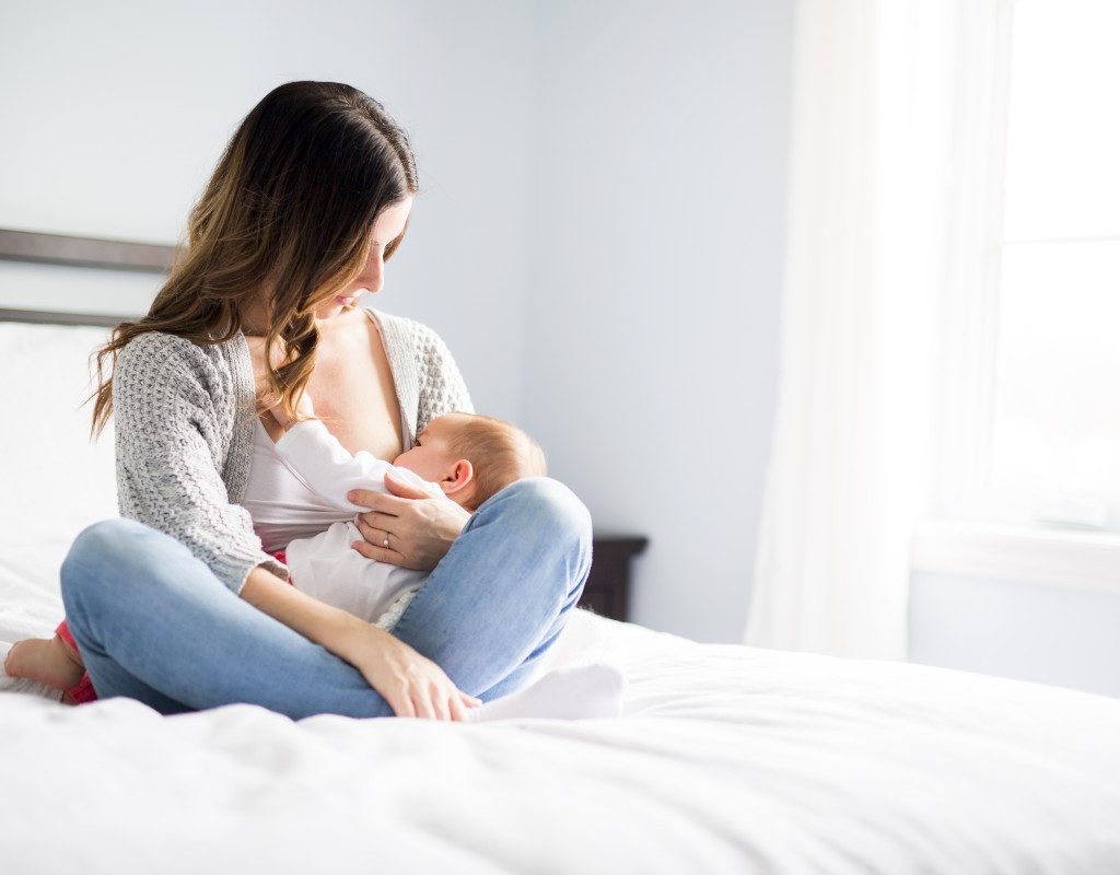Mom breastfeeding baby on bed