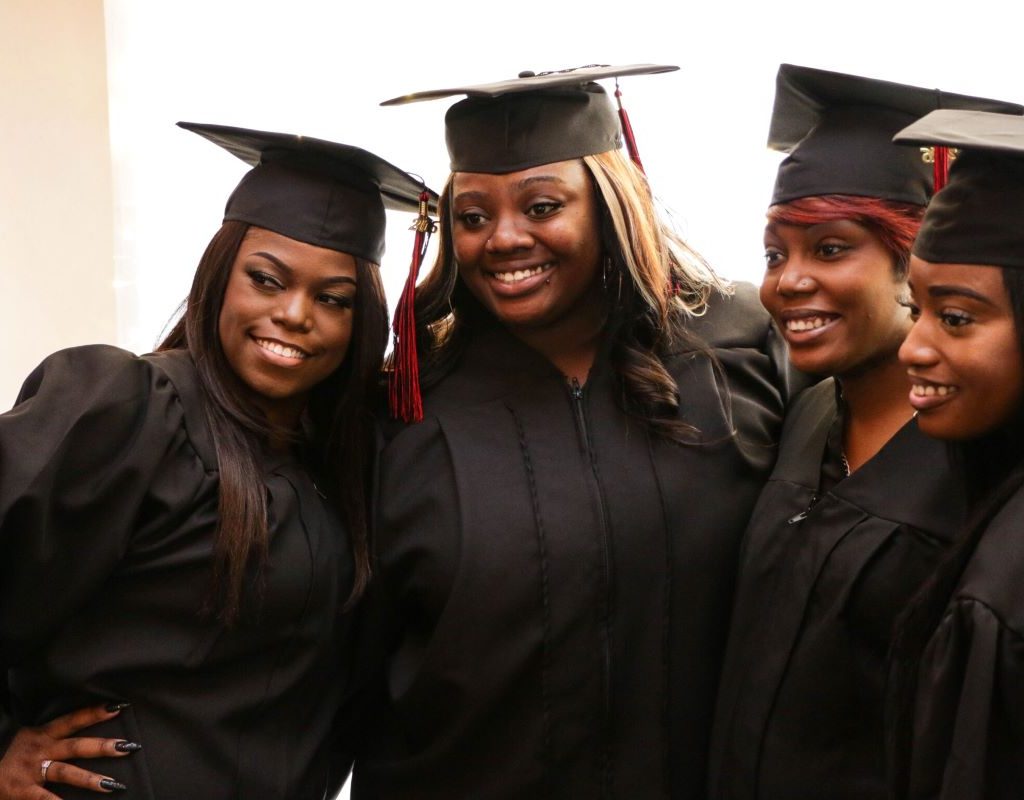 four graduates in caps and gowns