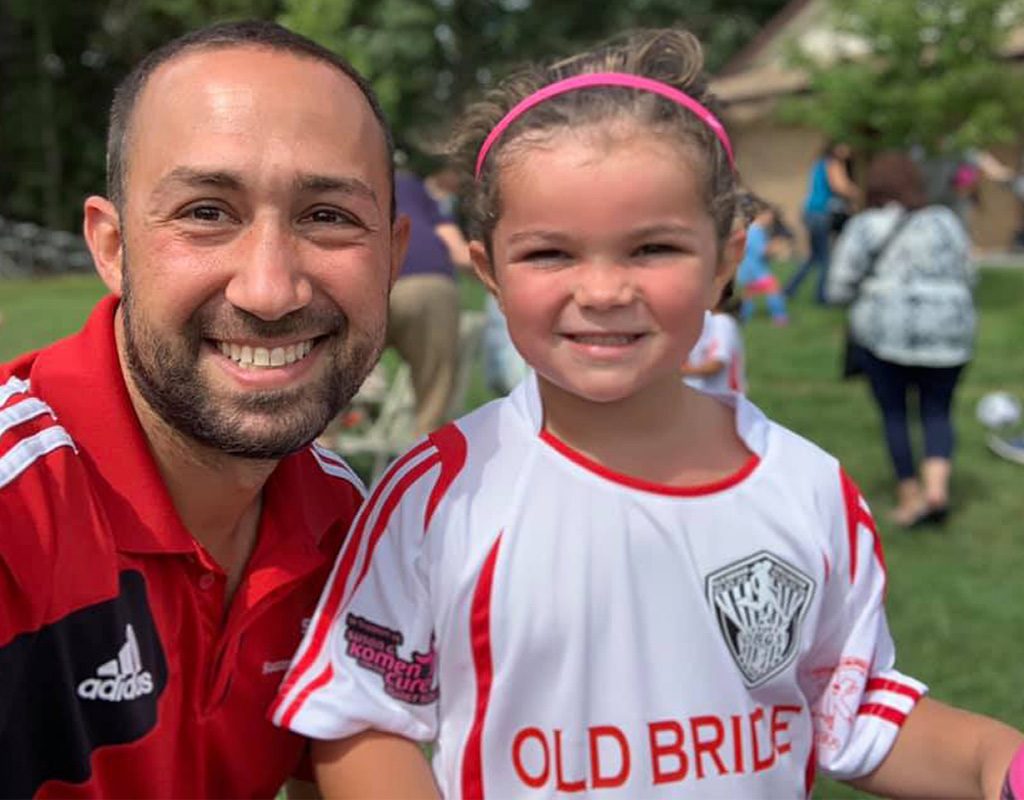 Coach Will Gould and smiling youth soccer player