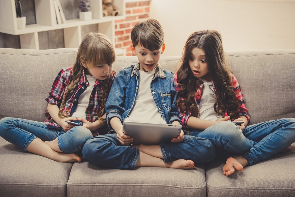 Kids on a couch playing on smart devices