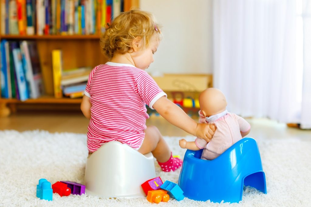 A toddler potty training with doll.