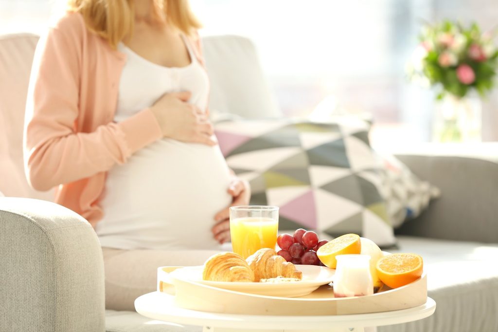 Pregnant woman with fruit and orange juice.