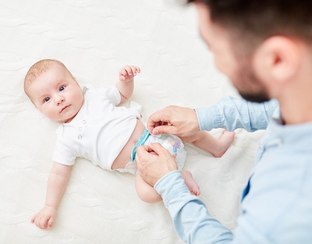 A dad making a disposable diaper change on a baby