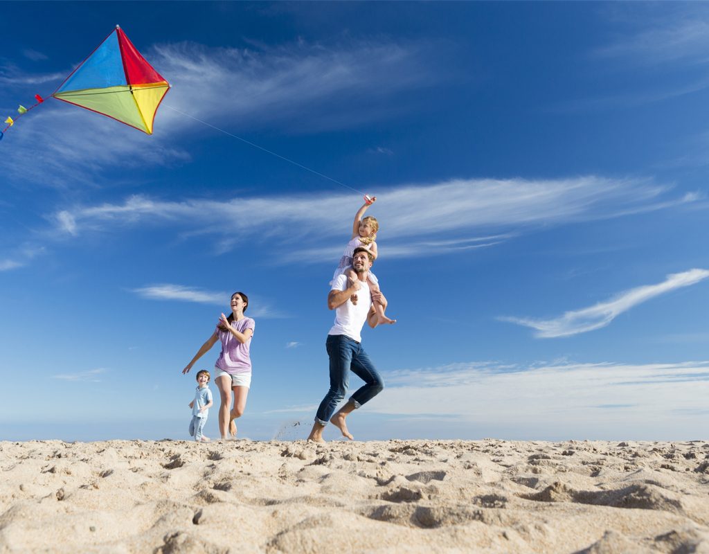 family having fun flying a kite on the beach