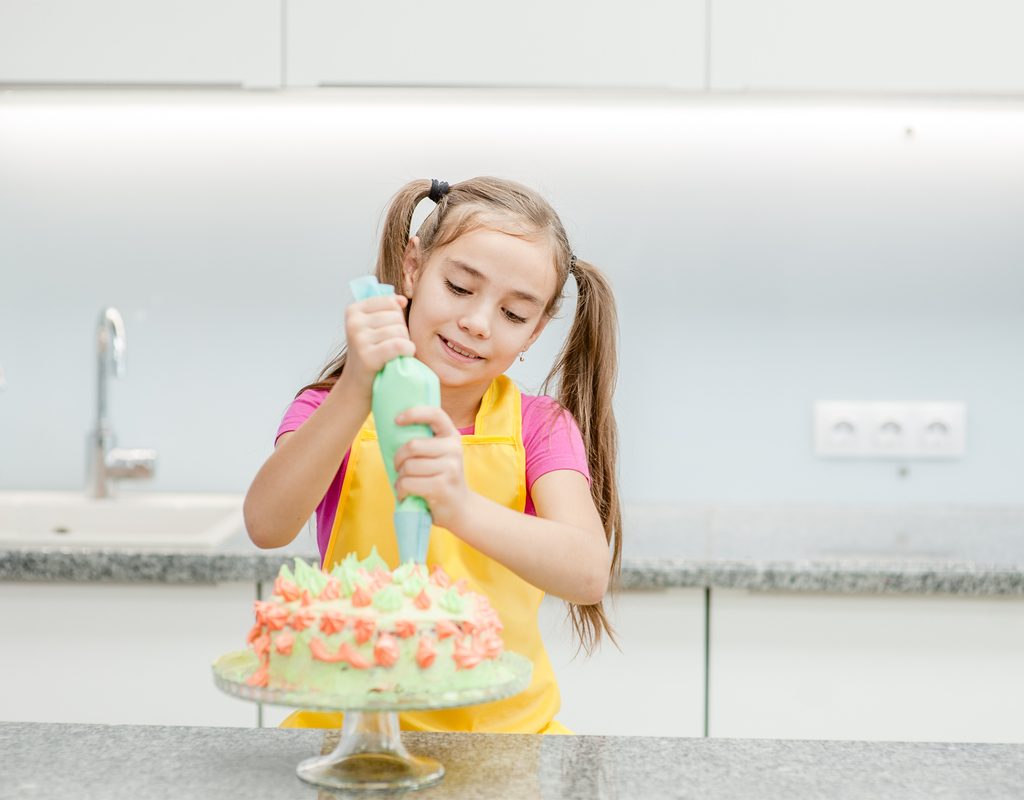 young girl decorating a cake in her kitchen