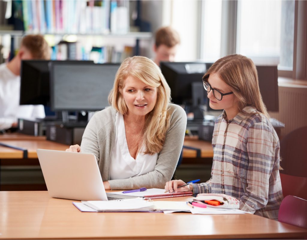 Woman tutoring a middle-school student in library