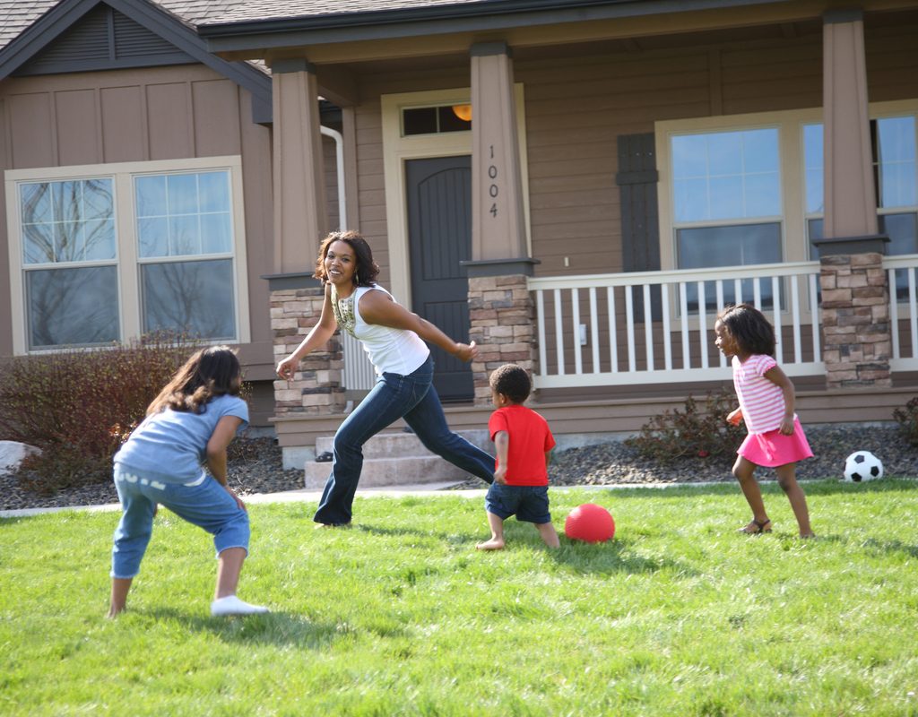 mom and kids having fun playing tag in the yard
