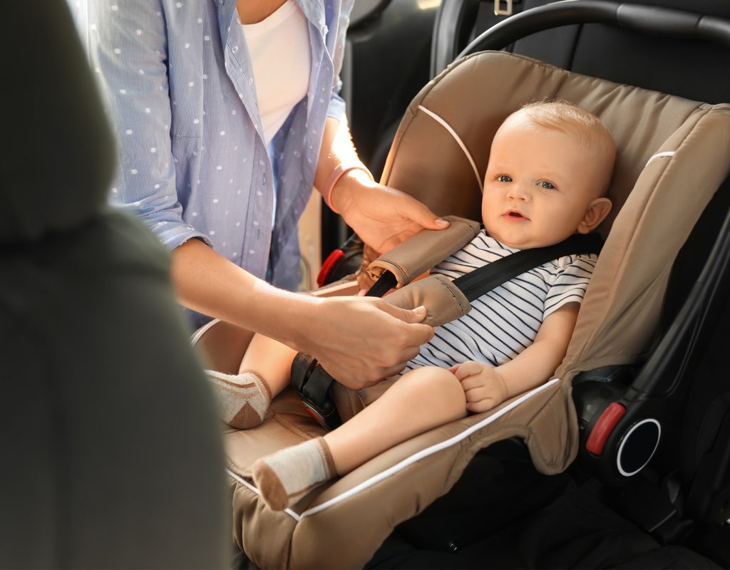 Mom buckling baby in a car seat