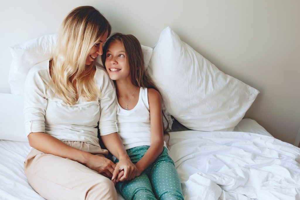 Mother and daughter talking in bed