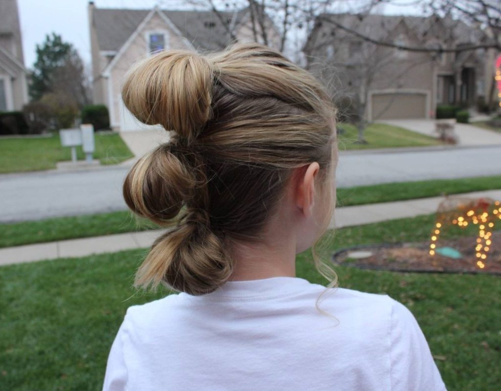 A young girl with her hair in a bubble style ponytail